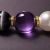 Extreme close-up of chatoyant cat's eye obsidian, radiant natural pearl, and polished 18k gold-filled spacer beads.