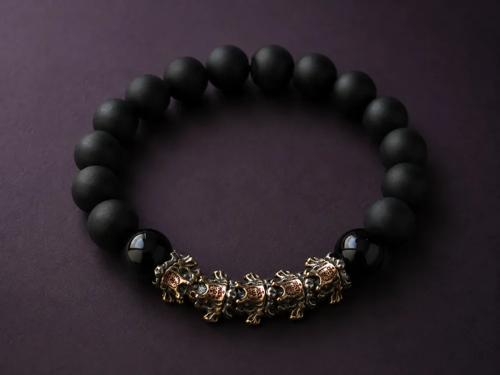 9Purple minimalist luxury dark zen beaded bracelet featuring matte and high-gloss black obsidian beads with vintage metal beast charms on a deep plum stone background.