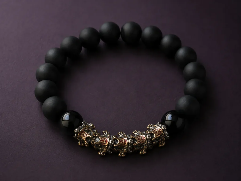 9Purple minimalist luxury dark zen beaded bracelet featuring matte and high-gloss black obsidian beads with vintage metal beast charms on a deep plum stone background.