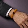 Earth Ground Yellow Agate Amethyst Bracelet Male Wrist Shot Earth Ground bracelet worn on male wrist with yellow agate beads, purple amethyst center bead, and gold-plated spacers