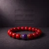 Fire Radiance bracelet with Nanhong agate beads, purple amethyst center bead, and gold-plated spacers on dark textured background