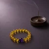 Metal Clarity Clear Citrine Amethyst Bracelet Incense Scene Metal Clarity bracelet with clear citrine beads, purple amethyst center bead, gold-plated spacers, and incense tray
