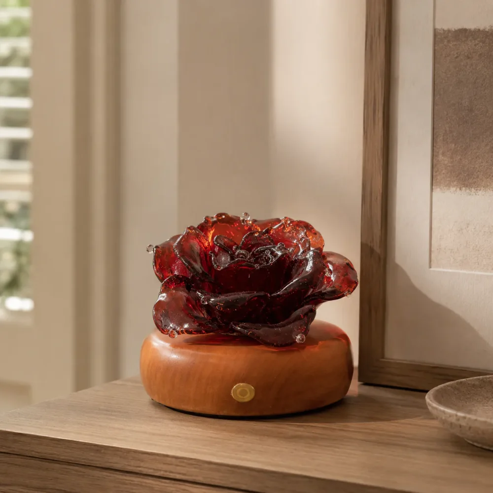 Vermilion Rose red glass rose light on a warm wood display base in a calm daytime interior