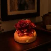 Vermilion Rose red glass rose light glowing at night on a warm wood display base
