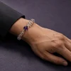 Water Flow bracelet worn on male wrist with clear quartz beads, purple amethyst center bead, and gold-plated spacers