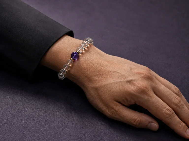 Water Flow bracelet worn on male wrist with clear quartz beads, purple amethyst center bead, and gold-plated spacers