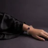 Water Flow bracelet worn on female wrist with clear quartz beads, purple amethyst center bead, and gold-plated spacers