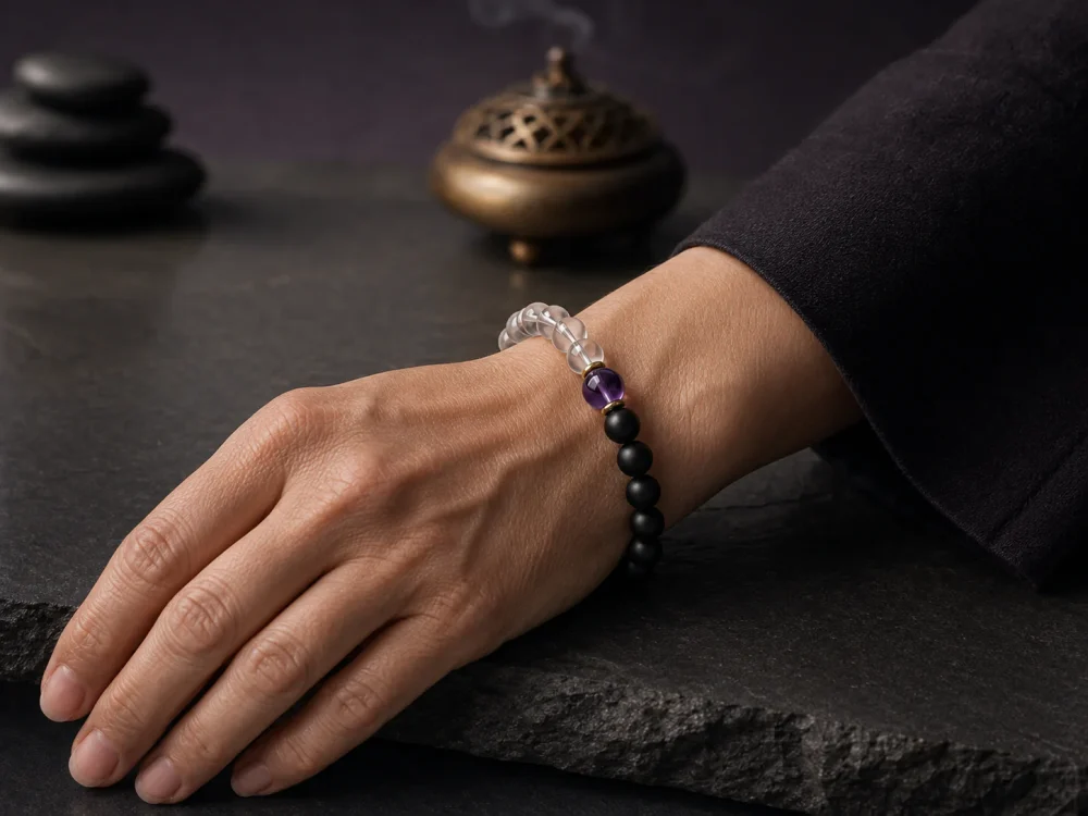 An elegant mature woman wearing the 9Purple Yin-Yang Balance bracelet on her wrist, resting her hand on a modern Zen slate desktop.