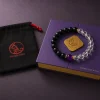 The 9Purple Yin-Yang bracelet draped obliquely across the top edge of the deep purple rectangular luxury packaging box with gold foil logo.