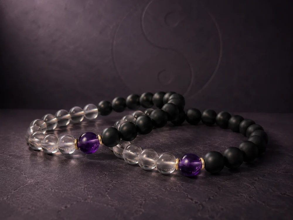 Two identical 9Purple Yin-Yang Balance bracelets intertwined in a non-intersecting elegant curve on a dark grey textured slate background.
