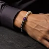 Sophisticated gentleman wearing the 9Purple gold-detailed Yin-Yang obsidian bracelet on wrist with a dark luxury shirt.