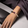 Close-up of a stylish hand wearing the 9Purple pearl and obsidian bracelet resting on a contemporary desk setup.