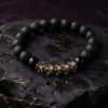 Luxury e-commerce still life photography of 9Purple obsidian bracelet resting on wet weathered black basalt rock with a withered ancient branch.