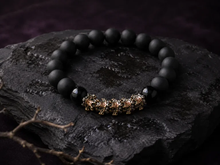Luxury e-commerce still life photography of 9Purple obsidian bracelet resting on wet weathered black basalt rock with a withered ancient branch.