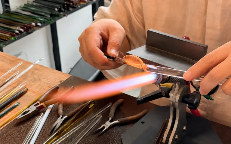 Artisan shaping borosilicate glass with a controlled torch flame during traditional lampworking
