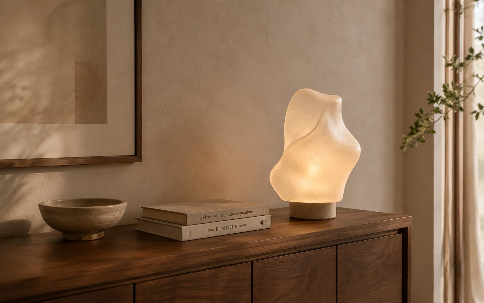 Abstract tabletop sculptural light displayed on a wood console in a warm neutral interior.